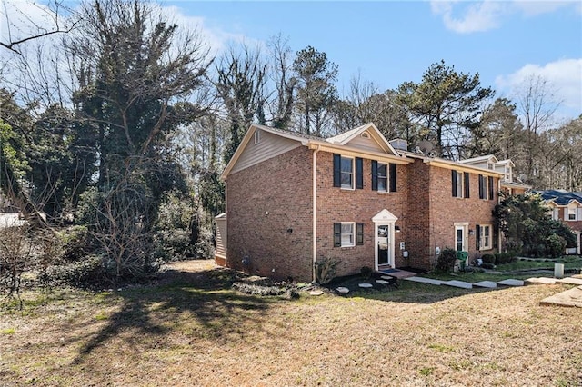 colonial inspired home featuring brick siding, a chimney, and a front yard