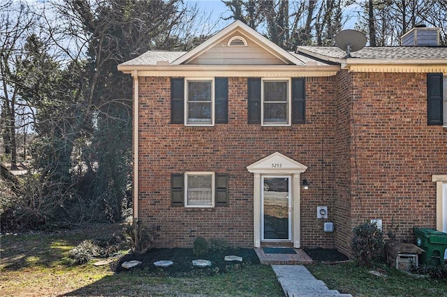 view of front of property with brick siding, a chimney, and a front lawn