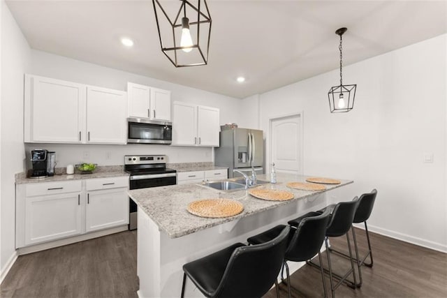 kitchen featuring pendant lighting, appliances with stainless steel finishes, an island with sink, and white cabinets