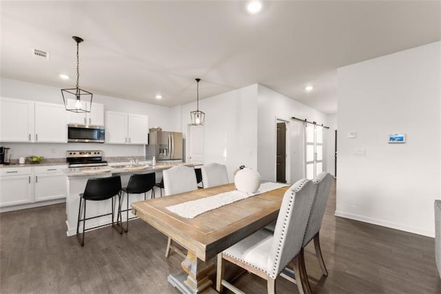 dining space with dark hardwood / wood-style floors and a barn door