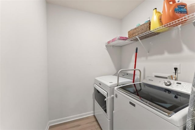 laundry area with separate washer and dryer and light hardwood / wood-style flooring