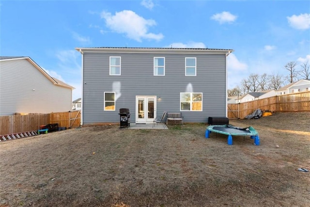 back of property with french doors and a trampoline