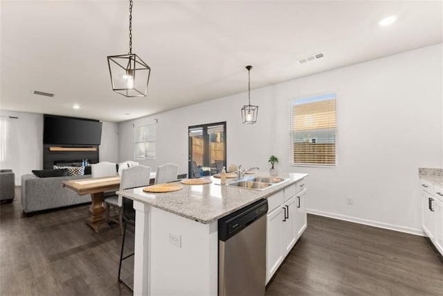 kitchen with a kitchen island with sink, hanging light fixtures, stainless steel dishwasher, and white cabinets