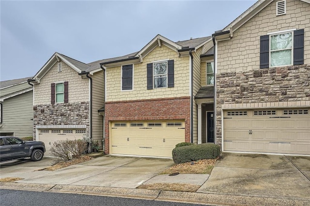 view of property featuring concrete driveway, brick siding, an attached garage, and stone siding