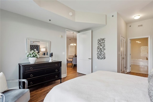 bedroom with a chandelier, dark hardwood / wood-style flooring, and ensuite bath