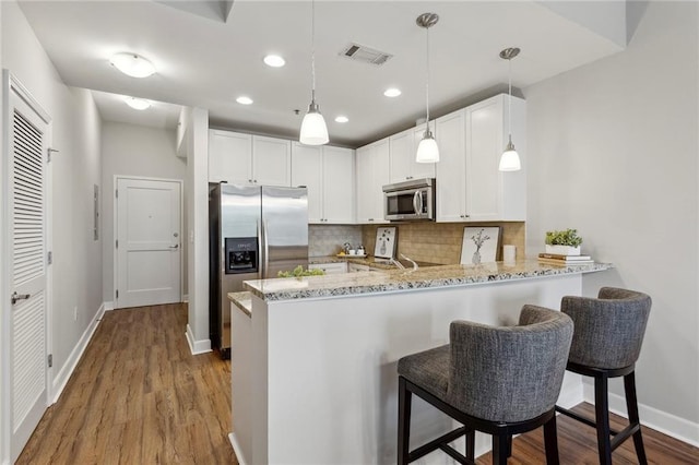 kitchen featuring decorative backsplash, white cabinetry, kitchen peninsula, and appliances with stainless steel finishes