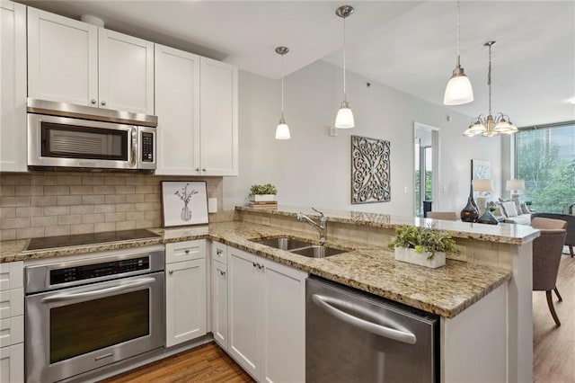 kitchen with kitchen peninsula, pendant lighting, stainless steel appliances, and white cabinetry