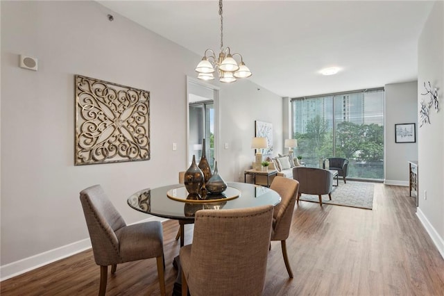 dining area featuring hardwood / wood-style floors, a notable chandelier, and a wall of windows