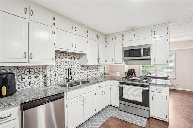 1752 Shadybrook Ct, Lawrenceville, GA 30043 - kitchen with appliances with stainless steel finishes, a sink, dark wood-style flooring, tasteful backsplash, and white cabinetry