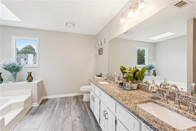 1752 Shadybrook Ct, Lawrenceville, GA 30043 - bathroom with a skylight, double vanity, a garden tub, wood finished floors, and baseboards