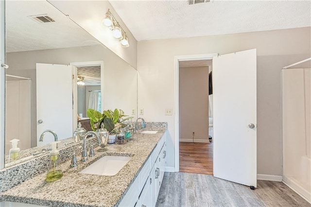 1752 Shadybrook Ct, Lawrenceville, GA 30043 - full bathroom with wood finished floors, ceiling fan, a shower, double vanity, and a textured ceiling