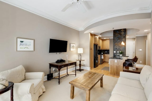 living room featuring light hardwood / wood-style flooring, ceiling fan, crown molding, and sink