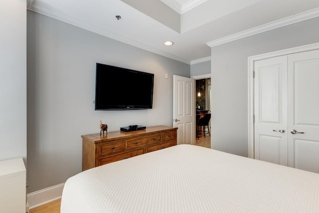 bedroom featuring a closet, ornamental molding, and light wood-type flooring