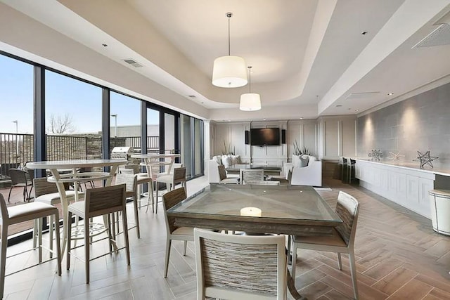 dining space featuring light parquet flooring and a raised ceiling