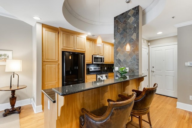 kitchen featuring backsplash, appliances with stainless steel finishes, light wood-type flooring, and a kitchen bar