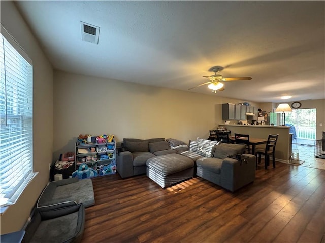 living area featuring dark wood-style flooring, a ceiling fan, and visible vents
