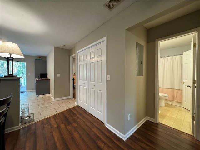 interior space featuring electric panel, visible vents, baseboards, and wood finished floors