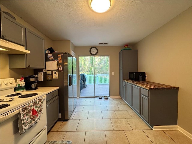 kitchen featuring light tile patterned flooring, gray cabinetry, under cabinet range hood, visible vents, and white range with electric stovetop