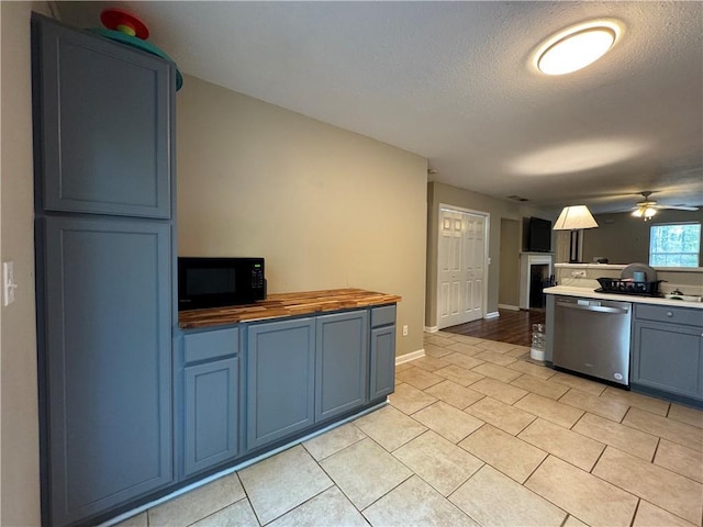 kitchen featuring butcher block countertops, black microwave, blue cabinetry, and dishwasher