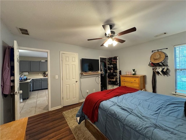bedroom featuring light wood finished floors, visible vents, a textured ceiling, and baseboards
