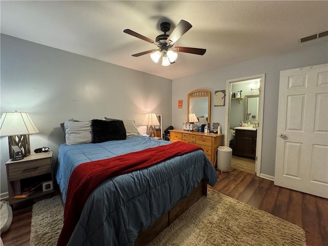 bedroom featuring dark wood-type flooring, ensuite bath, a ceiling fan, visible vents, and baseboards