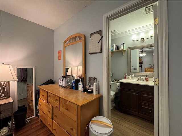bathroom featuring vanity, a textured ceiling, toilet, visible vents, and wood finished floors