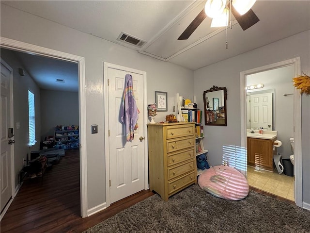 bedroom featuring connected bathroom, visible vents, wood finished floors, attic access, and a sink