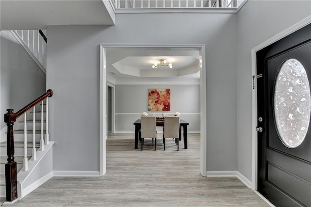 foyer entrance with light hardwood / wood-style flooring and a tray ceiling