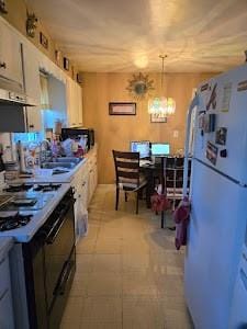 kitchen with white refrigerator, electric range, decorative light fixtures, extractor fan, and a chandelier