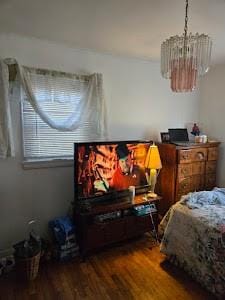 bedroom with hardwood / wood-style floors and a notable chandelier