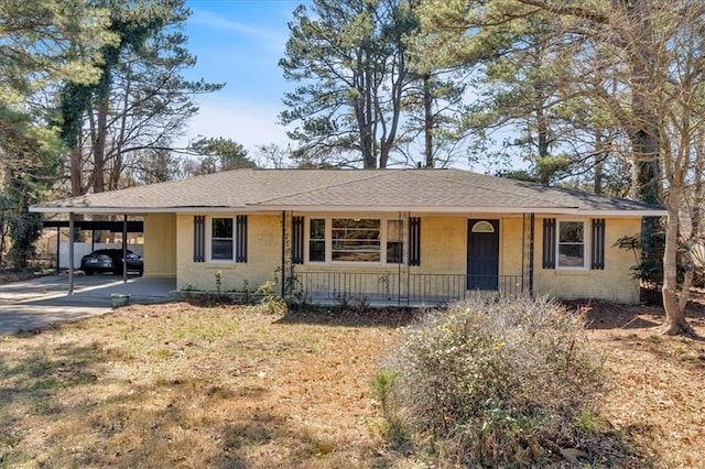 ranch-style home with a carport, concrete driveway, brick siding, and roof with shingles