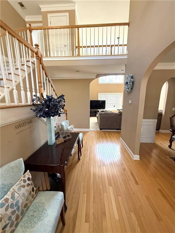 corridor featuring visible vents, arched walkways, stairway, hardwood / wood-style floors, and a high ceiling