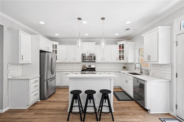 5710 Waters Edge Trl, Roswell, GA 30075 - kitchen with stainless steel appliances, a kitchen island, white cabinets, decorative backsplash, and crown molding