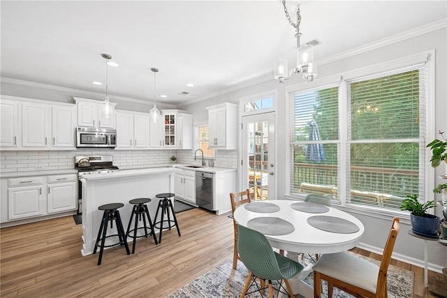 5710 Waters Edge Trl, Roswell, GA 30075 - kitchen with stainless steel appliances, decorative backsplash, white cabinets, a kitchen island, and crown molding