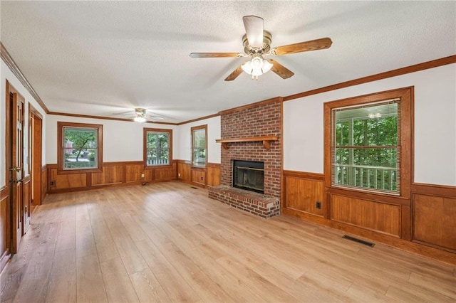 2110 Waterloo Cir, Lawrenceville, GA 30043 - unfurnished living room featuring a wainscoted wall, light wood-style flooring, a textured ceiling, a ceiling fan, and crown molding