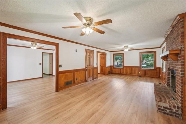 2110 Waterloo Cir, Lawrenceville, GA 30043 - unfurnished living room featuring light wood finished floors, wainscoting, ceiling fan, a fireplace, and a textured ceiling