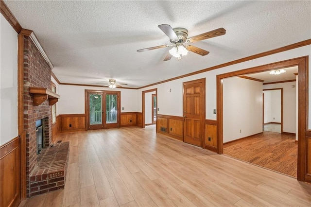 2110 Waterloo Cir, Lawrenceville, GA 30043 - unfurnished living room with wainscoting, ceiling fan, light wood-style flooring, a textured ceiling, and a brick fireplace