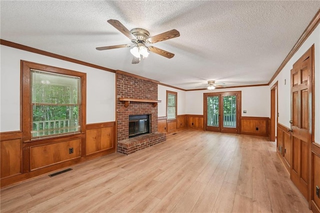 2110 Waterloo Cir, Lawrenceville, GA 30043 - unfurnished living room featuring a wainscoted wall, light wood-style flooring, a textured ceiling, a ceiling fan, and a fireplace