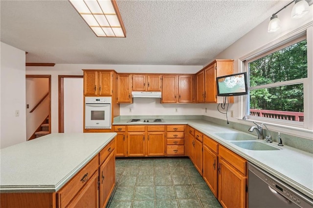 2110 Waterloo Cir, Lawrenceville, GA 30043 - kitchen featuring white oven, stainless steel dishwasher, under cabinet range hood, light countertops, and brown cabinets