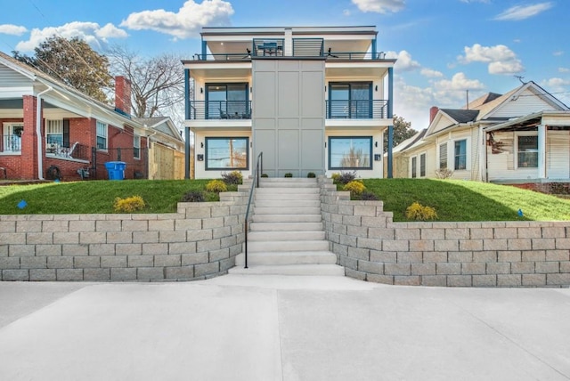 view of front of home featuring stucco siding, a balcony, and stairs