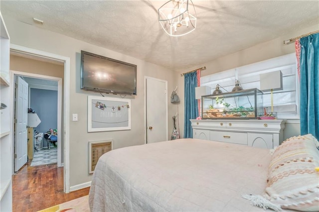 bedroom with hardwood / wood-style flooring, a notable chandelier, and a textured ceiling