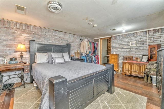 bedroom with hardwood / wood-style flooring and brick wall