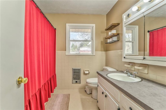 bathroom featuring heating unit, vanity, tile walls, and toilet