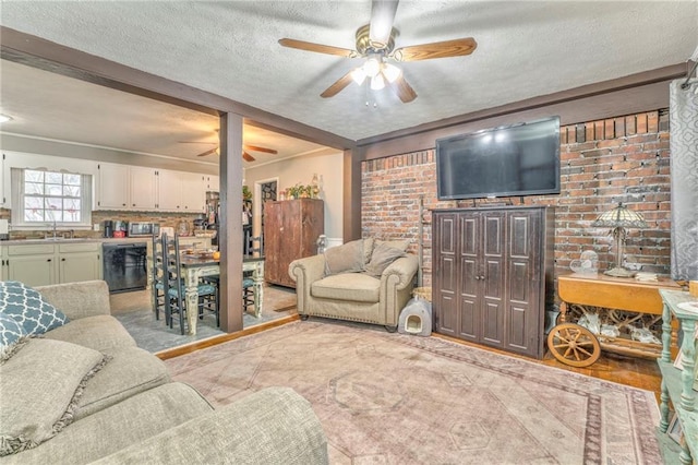 living room with ceiling fan, brick wall, sink, and a textured ceiling