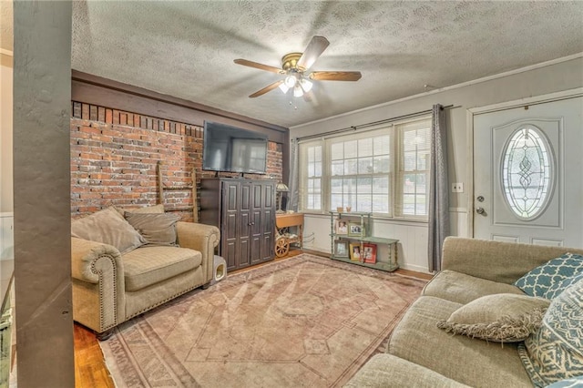 living room with hardwood / wood-style flooring, ceiling fan, crown molding, and a textured ceiling