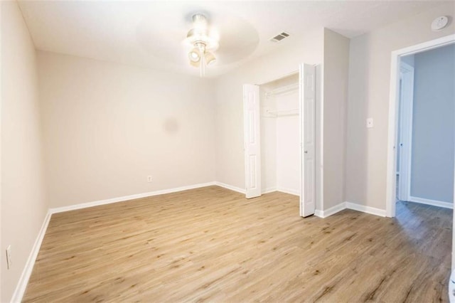 empty room featuring a ceiling fan, light wood-style floors, visible vents, and baseboards