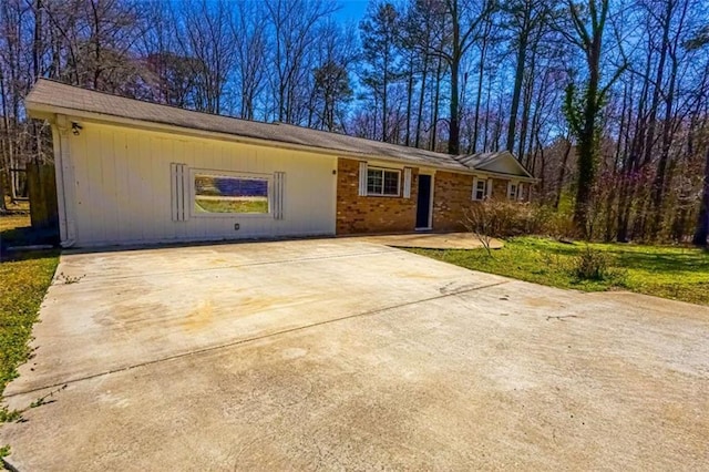 ranch-style home featuring concrete driveway, brick siding, and a front lawn