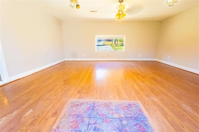 unfurnished room featuring visible vents, baseboards, and wood finished floors