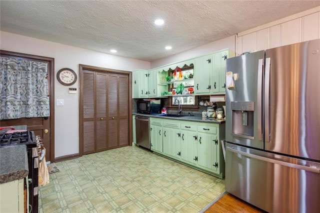 kitchen featuring appliances with stainless steel finishes, sink, green cabinets, and a textured ceiling