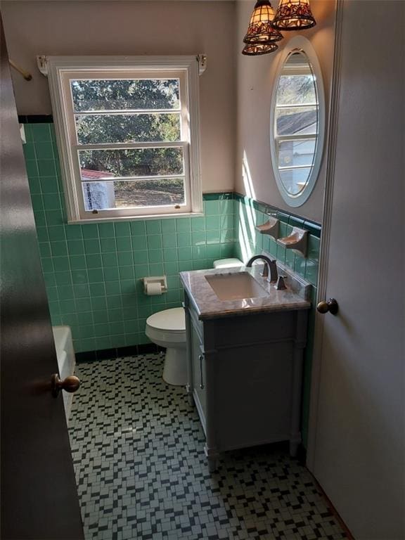 bathroom featuring vanity, toilet, and tile walls